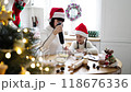 Mother and daughter baking in Christmas kitchen wearing Santa hats 118676336