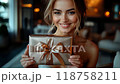 Woman holding a small wrapped gift box and smiling warmly 118758211
