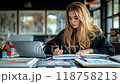 A blonde woman writing in a notebook while sitting in a modern office 118758213