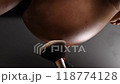 The master applies powder with a shimmer on the skin of a pregnant woman after an instant tanning procedure. Close-up of the tummy. Vertical photo.  118774128