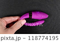 A woman holds a purple curved sex toy that vibrates and creates ripples on the surface of the water on a black background. Vertical video.  118774195