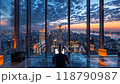 Man working at laptop near  large window at a city skyline during sunset 118790987