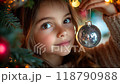A little girl gazing at her reflection in a silver Christmas ornament 118790988