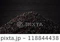 A pile of black fanning or broken loose leaf tea slowly rotates on a dark black background. Close-up, side view 118844438