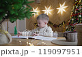 Boy designing Christmas decoration using miniature Christmas tree as example 119097951