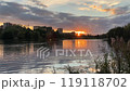 sunset over calm lake in overcast evening 119118702