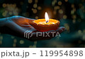diya light in a hand at dark background 119954898