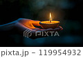 diya light in a hand at dark bokeh background 119954932