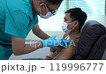 A man is getting a shot from a nurse. The nurse is wearing a mask and gloves. The man is wearing a mask as well. 119996777