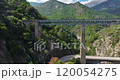 Drone flyby of a railway bridge in Corsicas dramatic mountains highlighting rugged landscape views during daytime 120054275