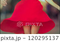 Woman in a vibrant red dress spins joyfully outdoors, her skirt billowing gracefully around her. The scene captures a carefree moment filled with energy and movement 120295137