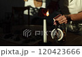 A woman lights a candle with a match, creating a cozy home atmosphere. Sunlight streams into the room, adding warmth and tranquility. 120423666