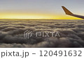 A  view of a golden sunrise seen from an airplane window, capturing the warm glow over a  of grey clouds.  Perfect for themes of travel, exploration, and the beauty of nature from above. 120491632