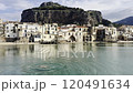 View of the beach in Cefalu with historic buildings and tourists enjoying a sunny day on the beach. Rocca di Cefalu in the background. Sicily travel destination. 120491634