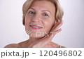 Closeup portrait of a confident woman in her 50s is gently touching her face, celebrating the beauty of graceful aging and selflove 120496802