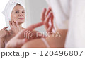 A mature woman in her 40s admires her beautiful skin while making gentle massage to her face and neck skin. Grace of aging and self care 120496807