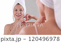 A graceful and mature woman in her 50s is joyfully touching her face, embracing the beauty of aging and her beloved skincare routines 120496978