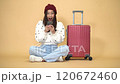 Happy young Asian tourist woman using smartphone to book a hotel room with baggage going to travel on holidays on yellow nude background 120672460