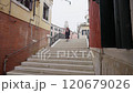 Young woman walk uphill in narrow street of traditional italian village with brick houses.  120679026