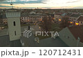 A peaceful evening scene of a town square with illuminated buildings, including a town hall and a monument. The image captures the calm atmosphere and the beauty of the urban landscape. 120712431