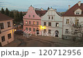 A charming street lined with colorful houses and a cobblestone road. The warm evening light creates a cozy atmosphere. 120712956