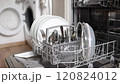 Female hand removing clean cutlery from a loaded dishwasher. Background of open wash machine  120824012