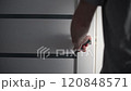 Man opening modern white door with metallic handle 120848571