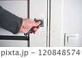 Man opening modern white door with metallic handle 120848574