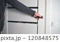 Man opening modern white door with metallic handle 120848575
