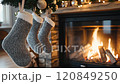 Christmas interior stockings hanging on fireplace with blurred fir tree and presents in background 120849250