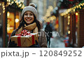 Happy woman holding christmas gift shopping while snowing in winter market 120849252