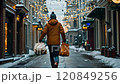 Man walking down snowy street carrying shopping bags during christmas time 120849256