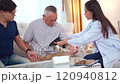 Senior Asian man having an annual health check by doctor. A female doctor comes to see a senior adult patient at home and checks his heart health and blood pressure. Doctor visiting elder patient's ho 120940812