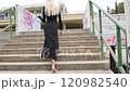 blond woman climbs stairs with black dress view from behind 120982540