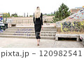 slow motion of a blond woman climbs stairs with black dress view from behind 120982541