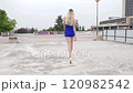 slow motion of a blond woman with short blue dress walks confidently 120982542