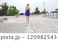 slow motion of a blond woman with short blue dress walks confidently 120982543