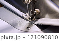 close up of a sewing machine needle in the activity of someone sewing clothes 121090810