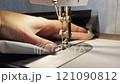 close up of a sewing machine needle in the activity of someone sewing clothes 121090812
