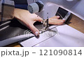 close up of a sewing machine needle in the activity of someone sewing clothes 121090814