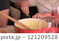 Cozy Swiss fondue setup with melted cheese, bread, pickles, and wine on a rustic table. advertising 121209528
