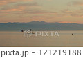 Serene scene of person sup boarding on a calm sea during sunset on background of mountains 121219188