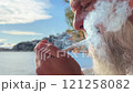 Close-up of a man with a gray beard lighting a cigarette 121258082