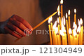 a woman puts a candle in the church. a woman's hand holds a candle in the church 121304949