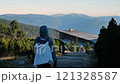 A hiker is making their way towards stunning modern architecture nestled in the scenic mountains 121328587