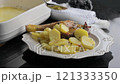 Elegant roasted duck leg served with golden potatoes and fresh herbs on a rustic plate.  121333350