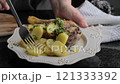 Elegant roasted duck leg served with golden potatoes and fresh herbs on a rustic plate.  121333392