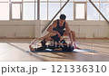 Beautiful athletic couple in sportswear sit in yoga poses on yoga mats in the gym in the morning, fitness girl and trainer man meditate in light fitness room, Health lifestyle and beauty concept 4K 121336310