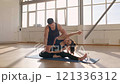 Fitness trainer practicing yoga with a young woman apprentice on yoga mats in the gym in the morning, fitness girl Generation Z and trainer man yoga workout in light fitness room 4K UHD B-Roll footage 121336312