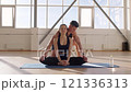 Fitness trainer practicing yoga with a young woman apprentice on yoga mats in the gym in the morning, fitness girl Generation Z and trainer man yoga workout in light fitness room 4K UHD B-Roll footage 121336313
